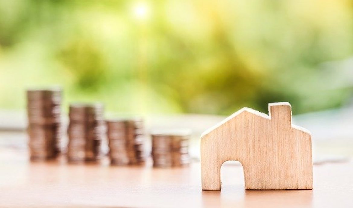 wooden house model with coins in background