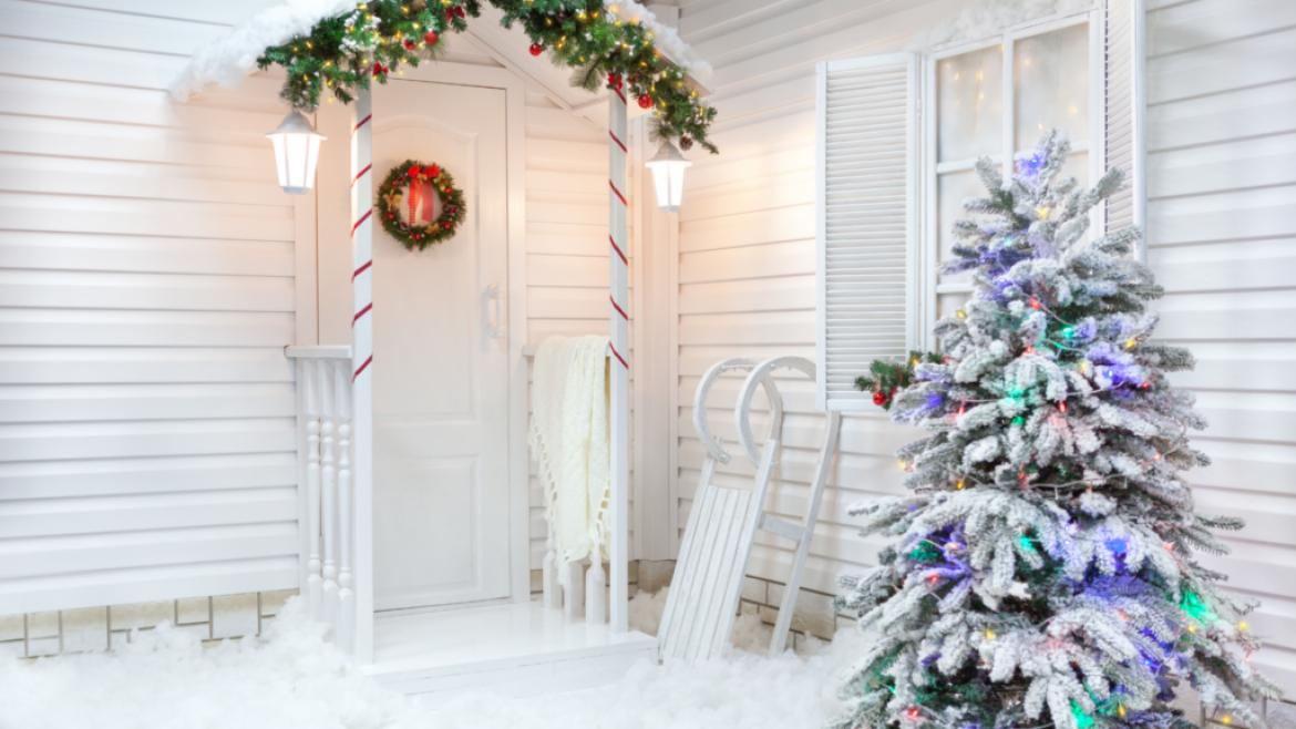 snow covered house porch with Christmas tree by door