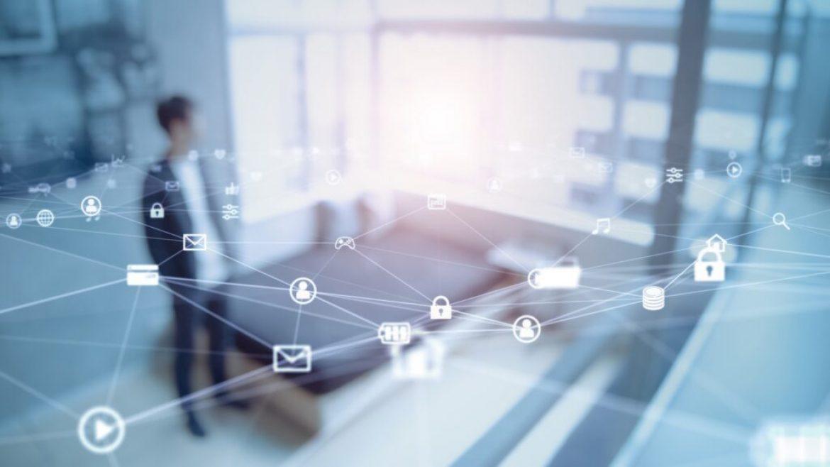 man standing in room with digital icons in foreground for smart home tech