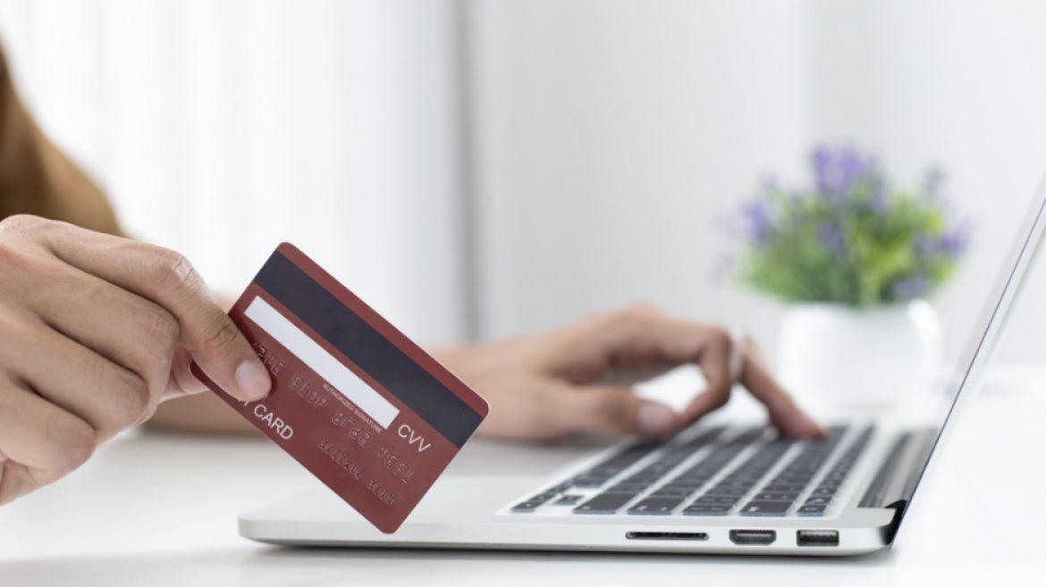 person typing on laptop with credit card in hand