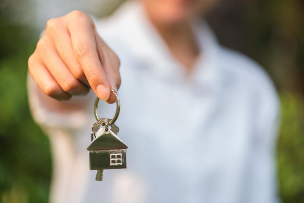 man holding house key towards camera