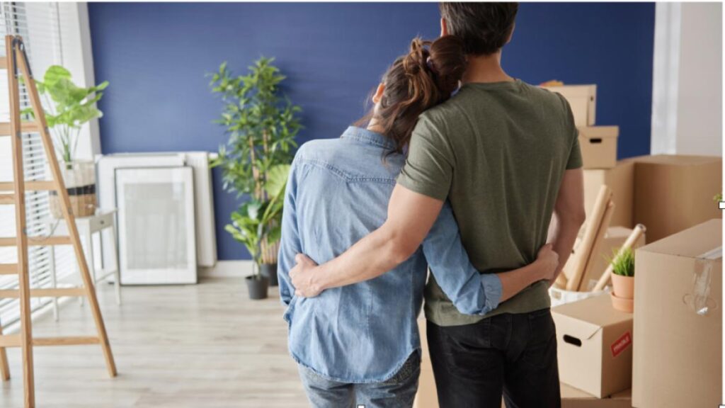 couple holding each other looking at wall and moving boxes