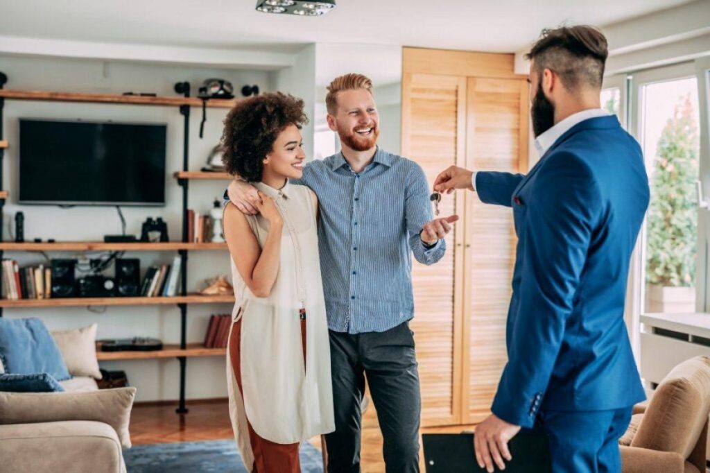 real estate agent giving keys to new home to couple