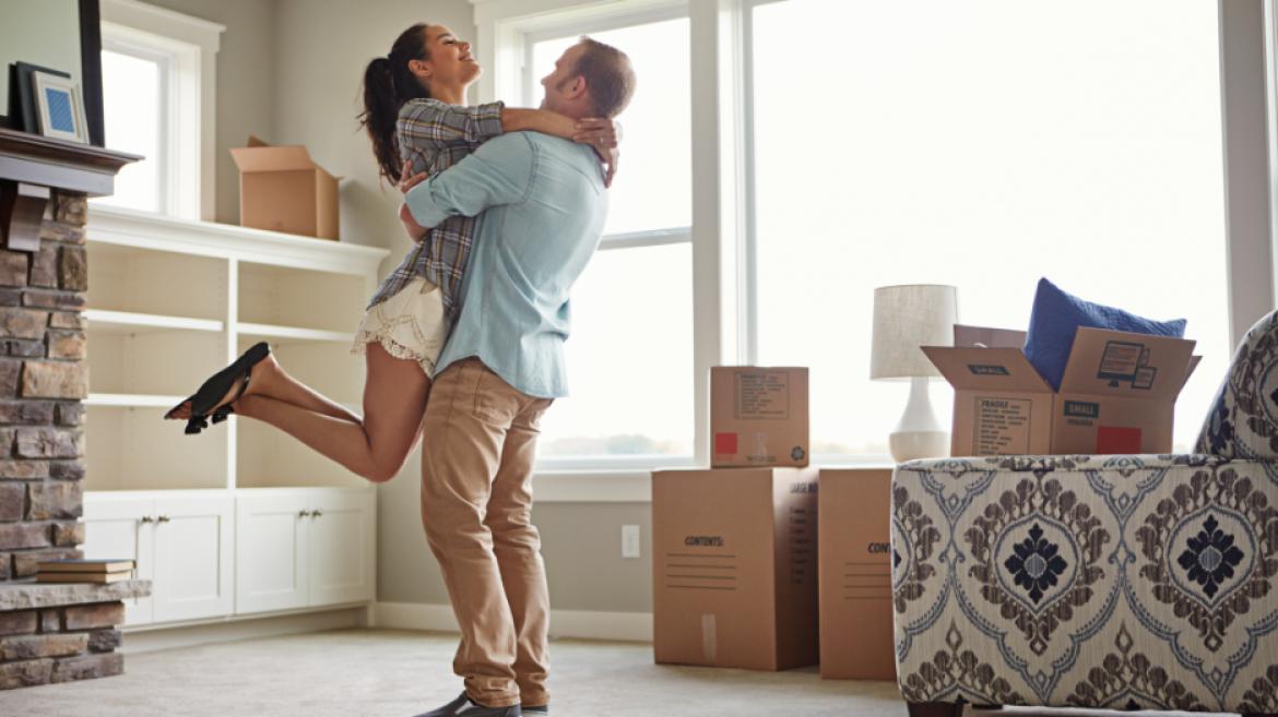 man holding woman in new home with moving boxes in background