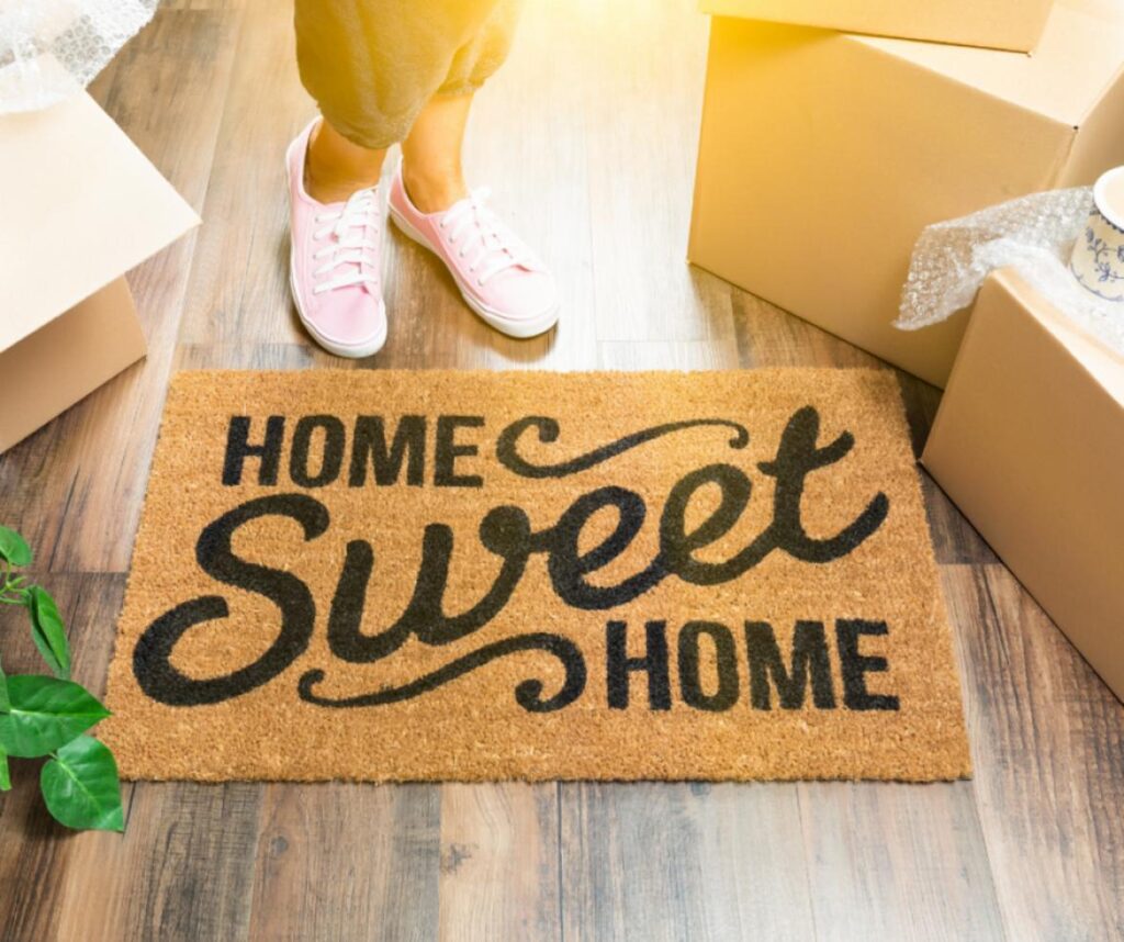 woman standing next to home sweet home floor mat